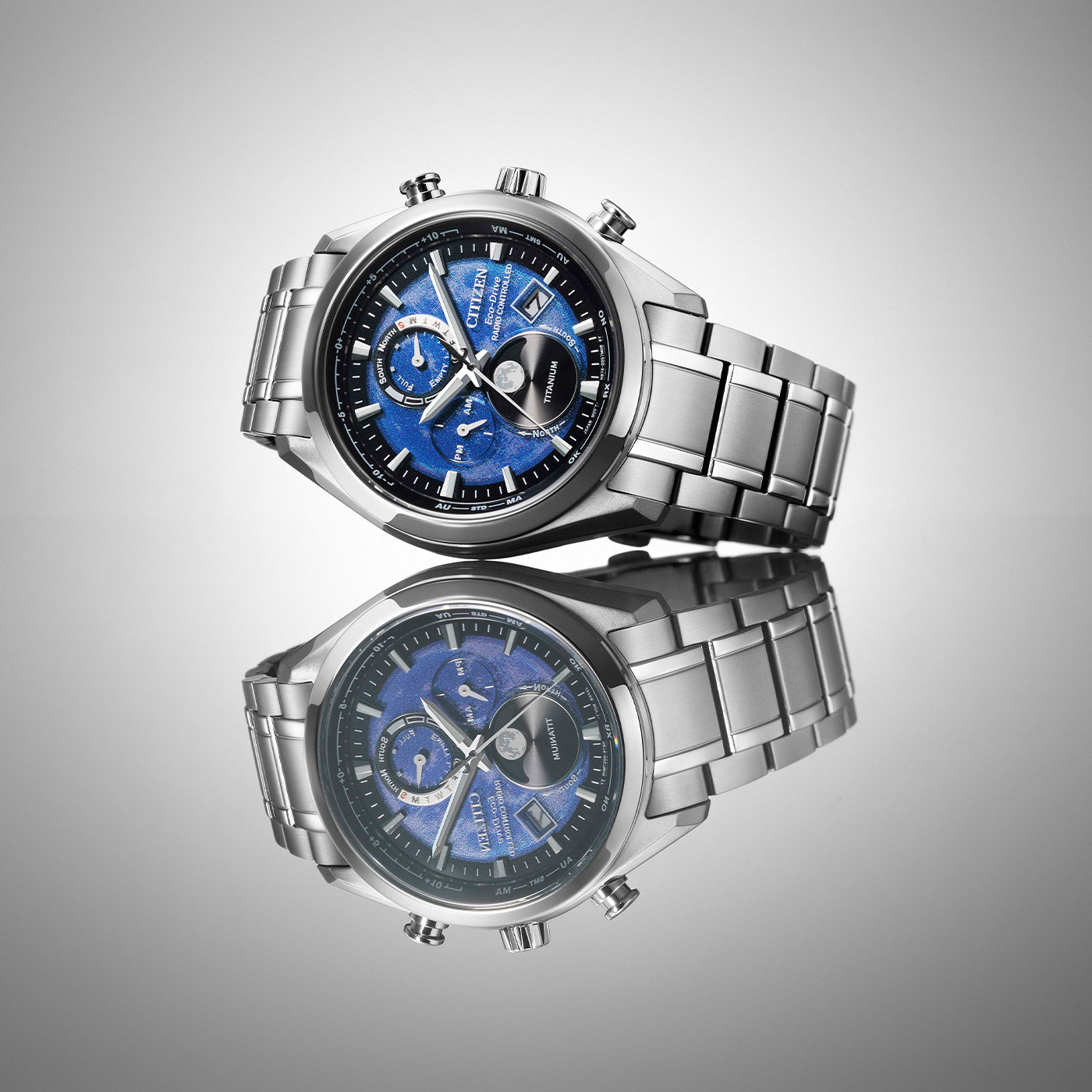 Citizen horloge met blauwe wijzerplaat en titanium band, weerspiegeld op een oppervlak.
