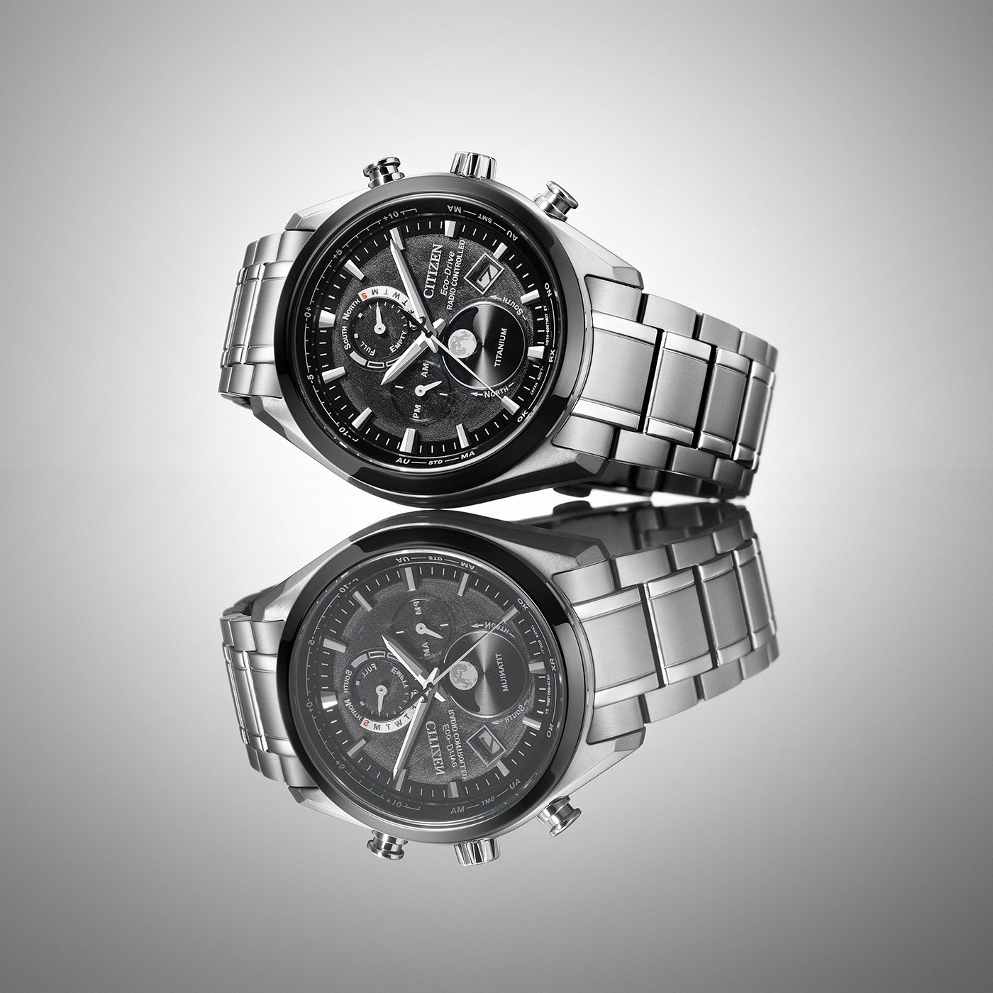 Citizen horloge met zwarte wijzerplaat en zilveren band, weerspiegeld op een oppervlak.