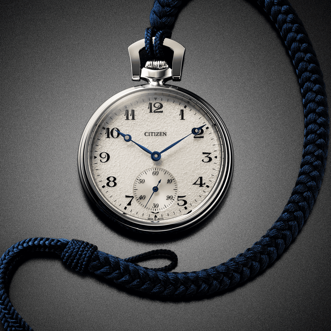 Close-up van een Citizen zakhorloge met een blauw gevlochten koord op een grijze achtergrond.