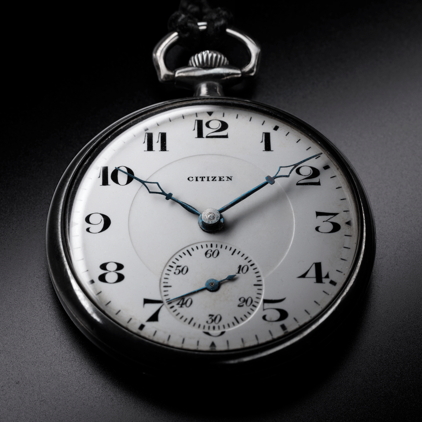 Close-up van een Citizen zakhorloge, met de tijd en details op een zwarte achtergrond.