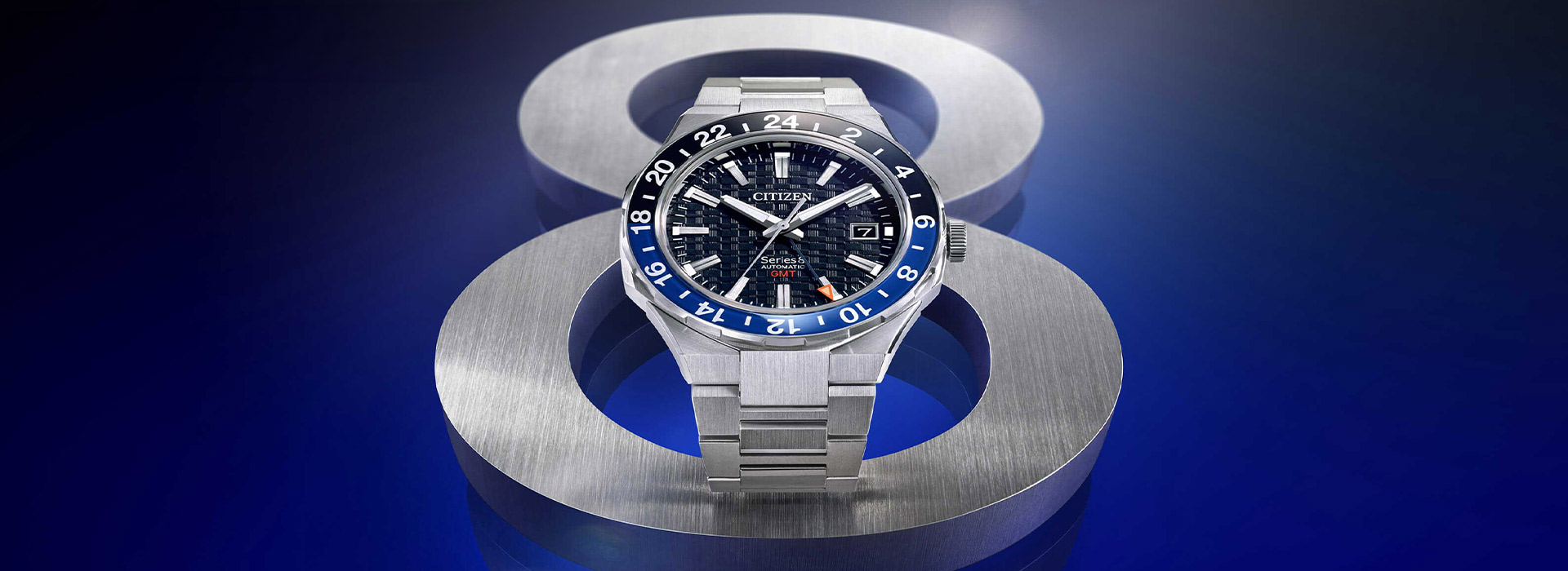 Citizen Series 8 automatische GMT-horloge op een blauwe achtergrond met metalen accenten.