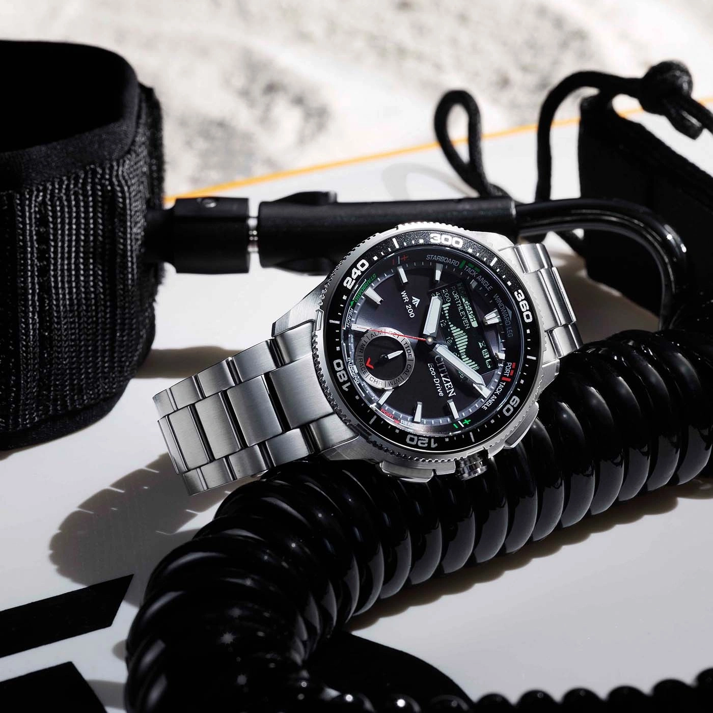 Een horloge op een surfplank met riem en spiraalkoord.