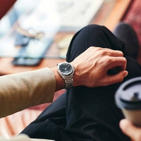 Man met Citizen horloge, zittend met koffie, close-up. Stijlvol en elegant.