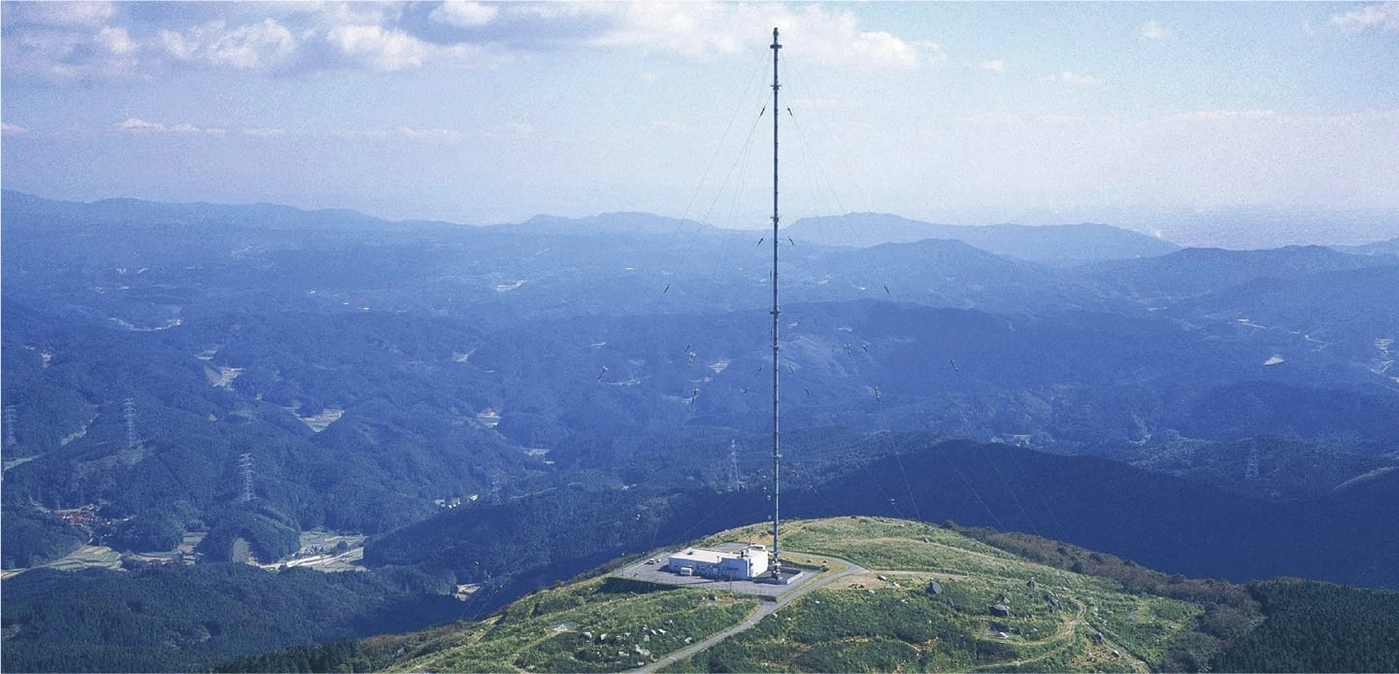 Een hoge radiotoren op een berg met een prachtig landschap.