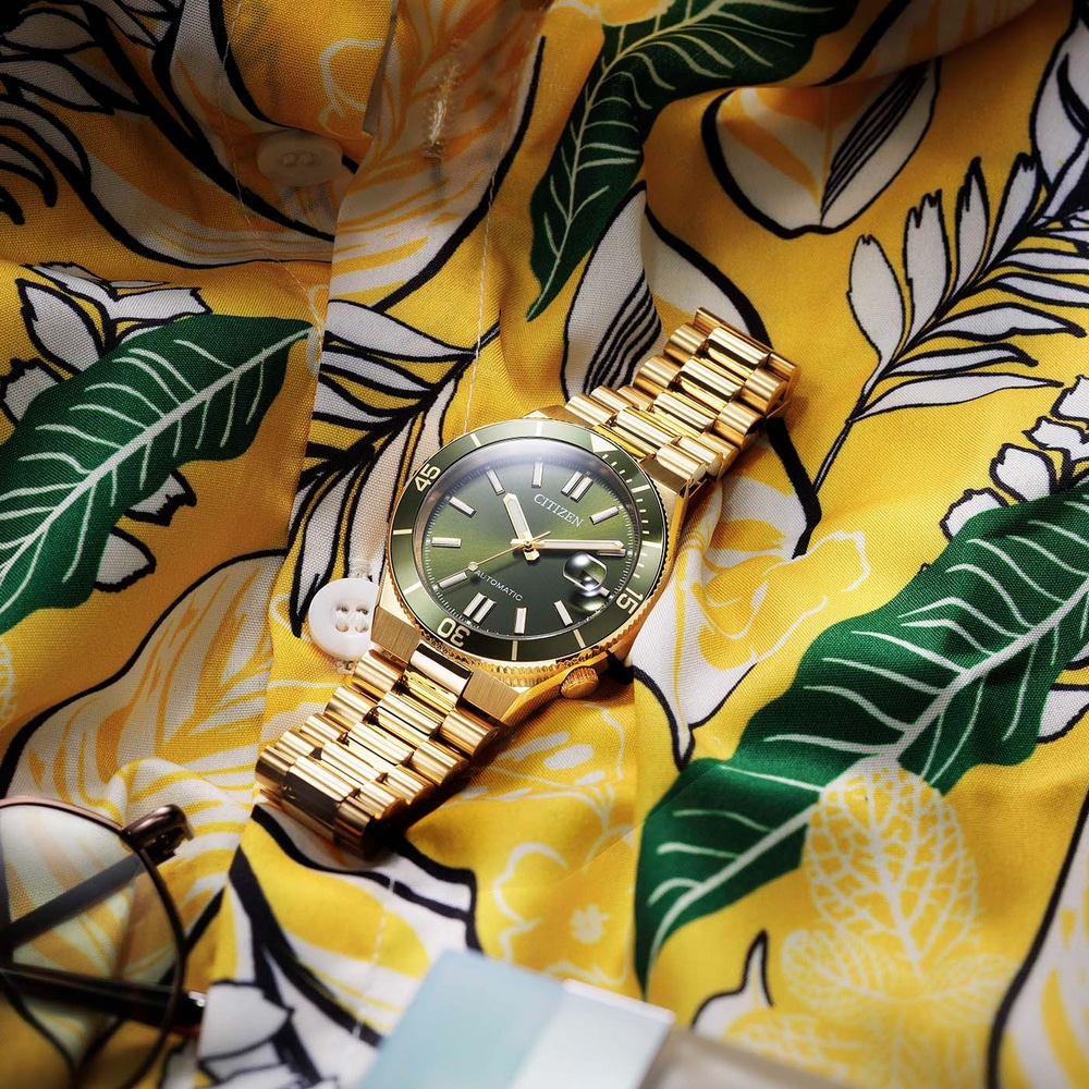 Een gouden Citizen horloge op een geel bloemenhemd.