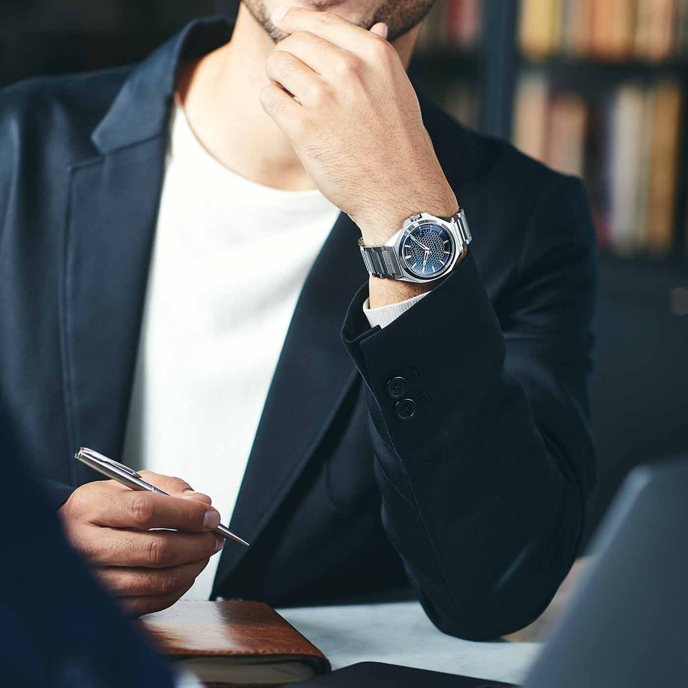 Man in pak met horloge, houdt pen vast, denkt na, zakelijke bijeenkomst, kantoor