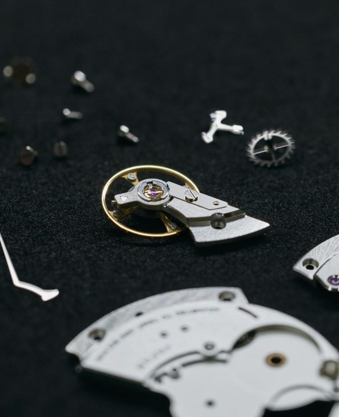 Close-up van horlogeonderdelen op zwarte ondergrond, ingewikkelde details zichtbaar.