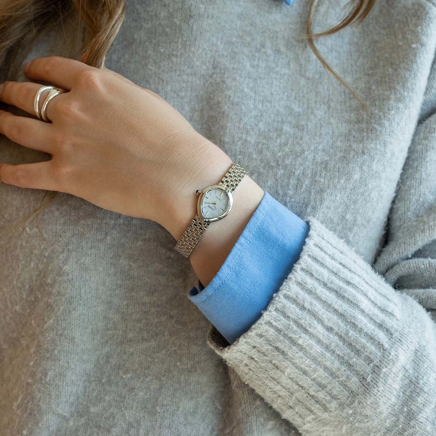 Vrouw met trui, shirt, horloge en ring.