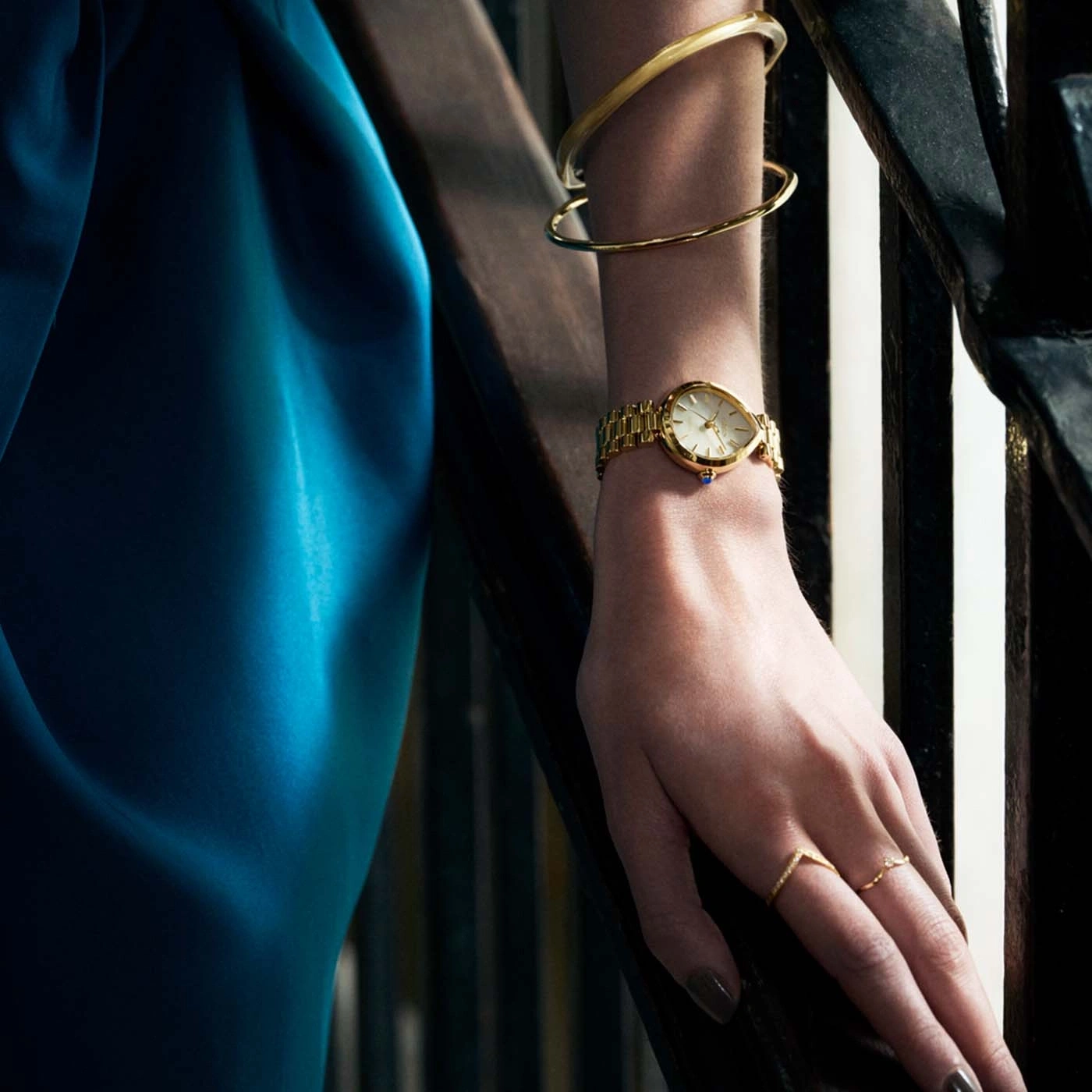 Vrouwenhand met horloge, armbanden en ringen op trap.
