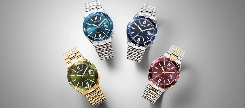 Vier Citizen horloges met verschillende gekleurde wijzerplaten en metalen banden.
