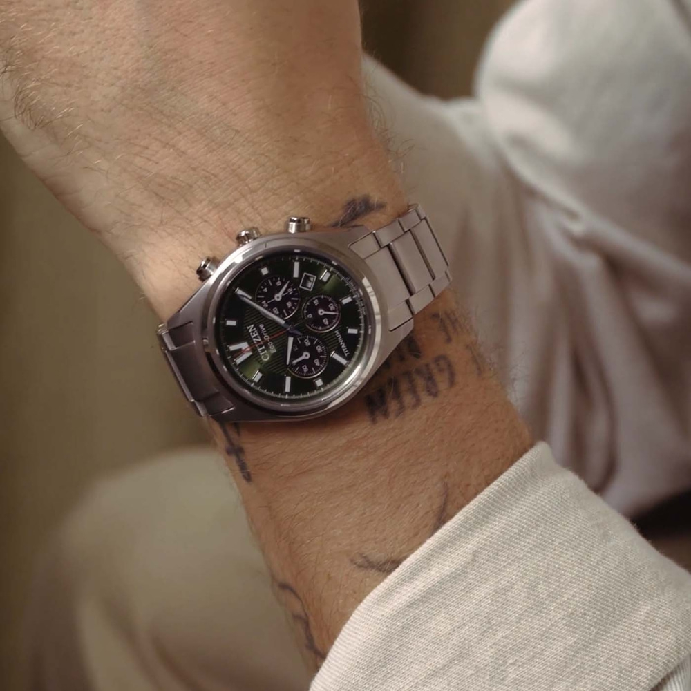 Een man draagt een zilveren Citizen Eco-Drive horloge met groene wijzerplaat.