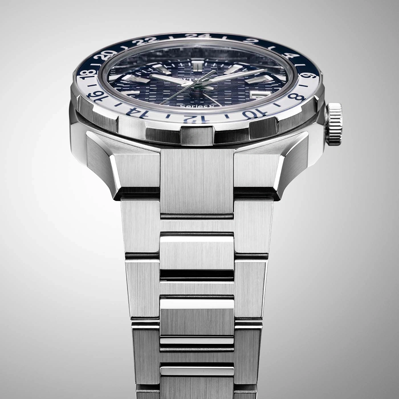 Close-up van een zilveren horloge met een blauw-witte bezel en een metalen band.