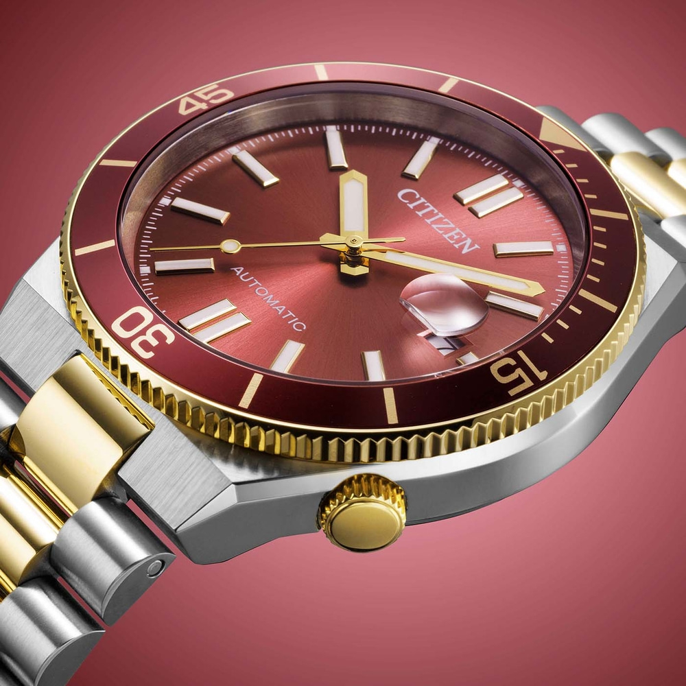 Close-up van een Citizen automatisch horloge met rode wijzerplaat en gouden accenten.