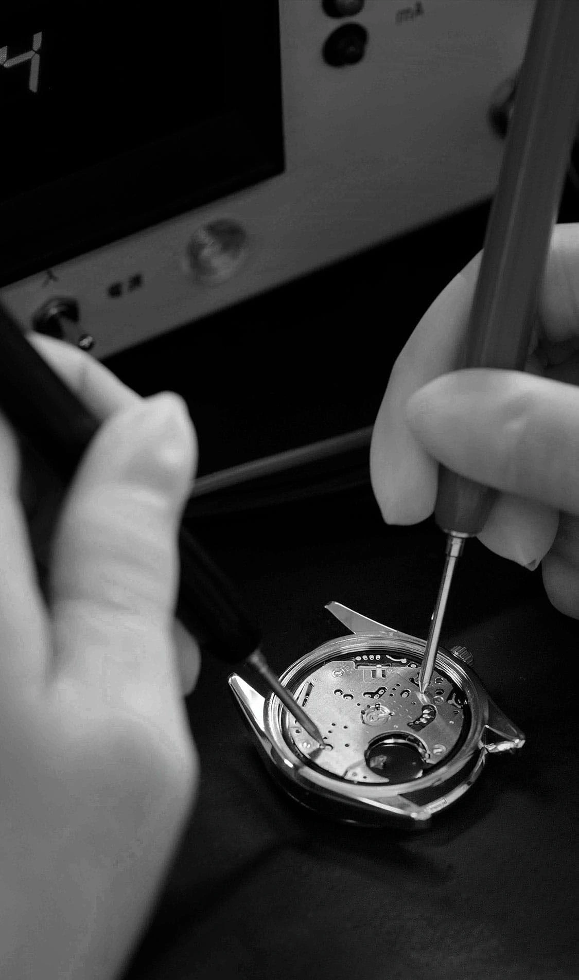 Horlogereparatie met gereedschap, close-up van handen en horlogemechanisme.