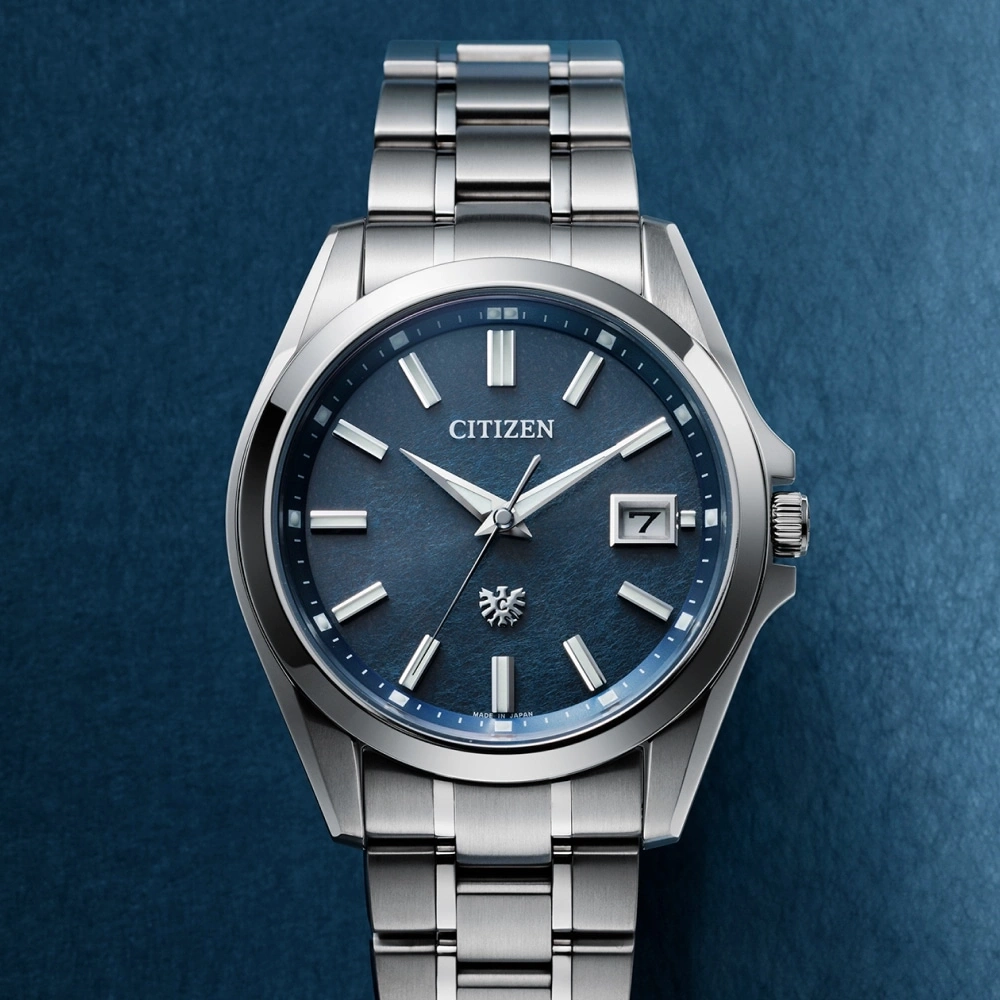 Citizen horloge met blauwe wijzerplaat en zilveren armband op blauwe achtergrond