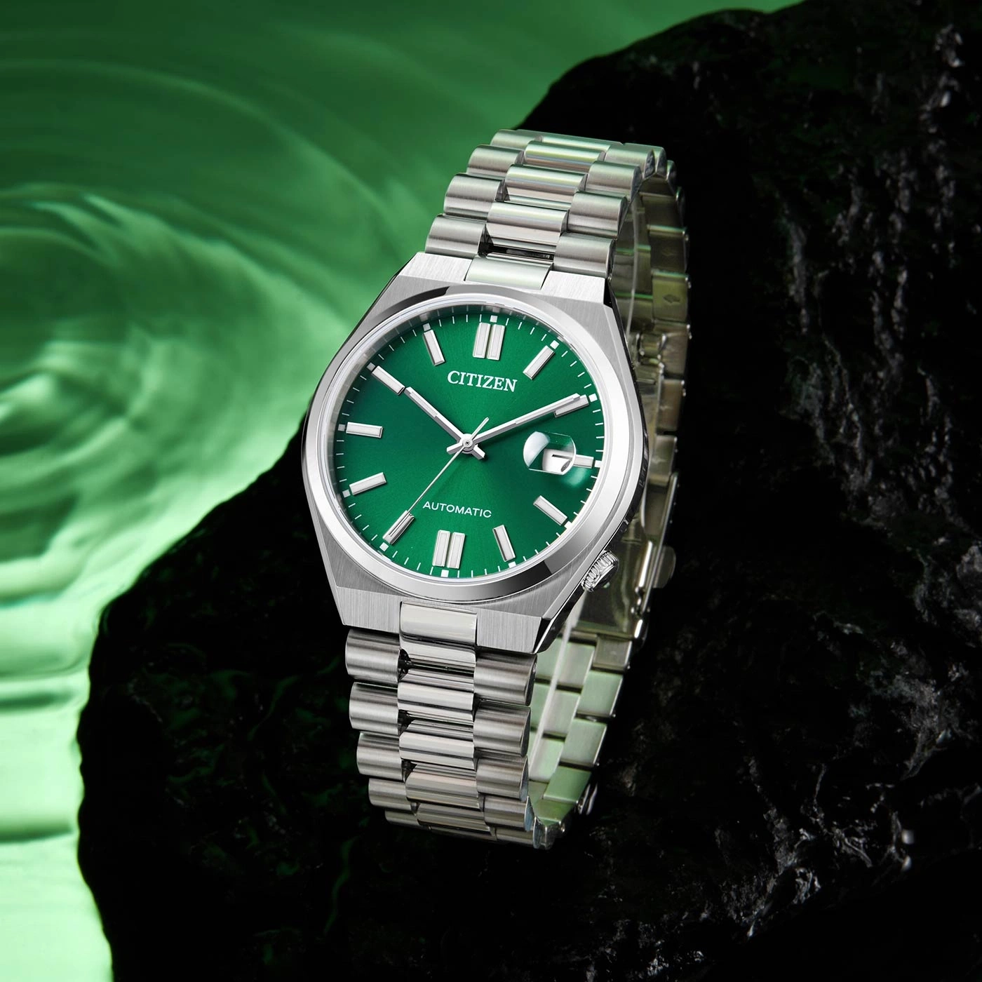 Citizen horloge met groene wijzerplaat en zilveren band op donkere ondergrond.