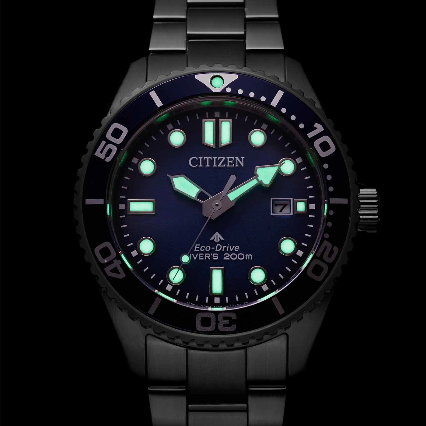 Citizen horloge met lichtgevende wijzers en markeringen, zwarte bezel, blauwe wijzerplaat en datumweergave.