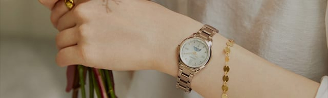 Een persoon die een horloge en een armband draagt, bloemen vasthoudt.