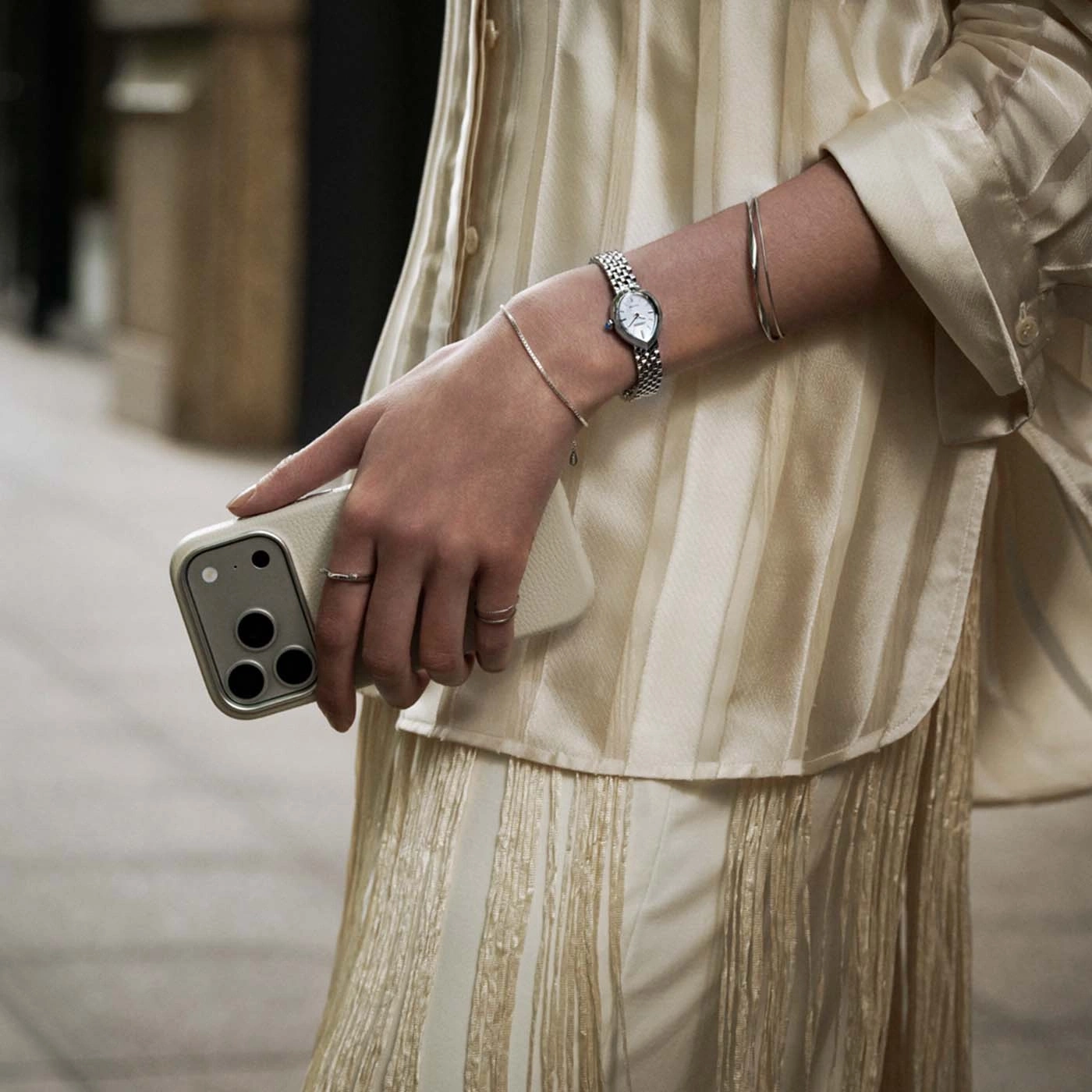 Close-up van een vrouwenarm met horloge en telefoon.