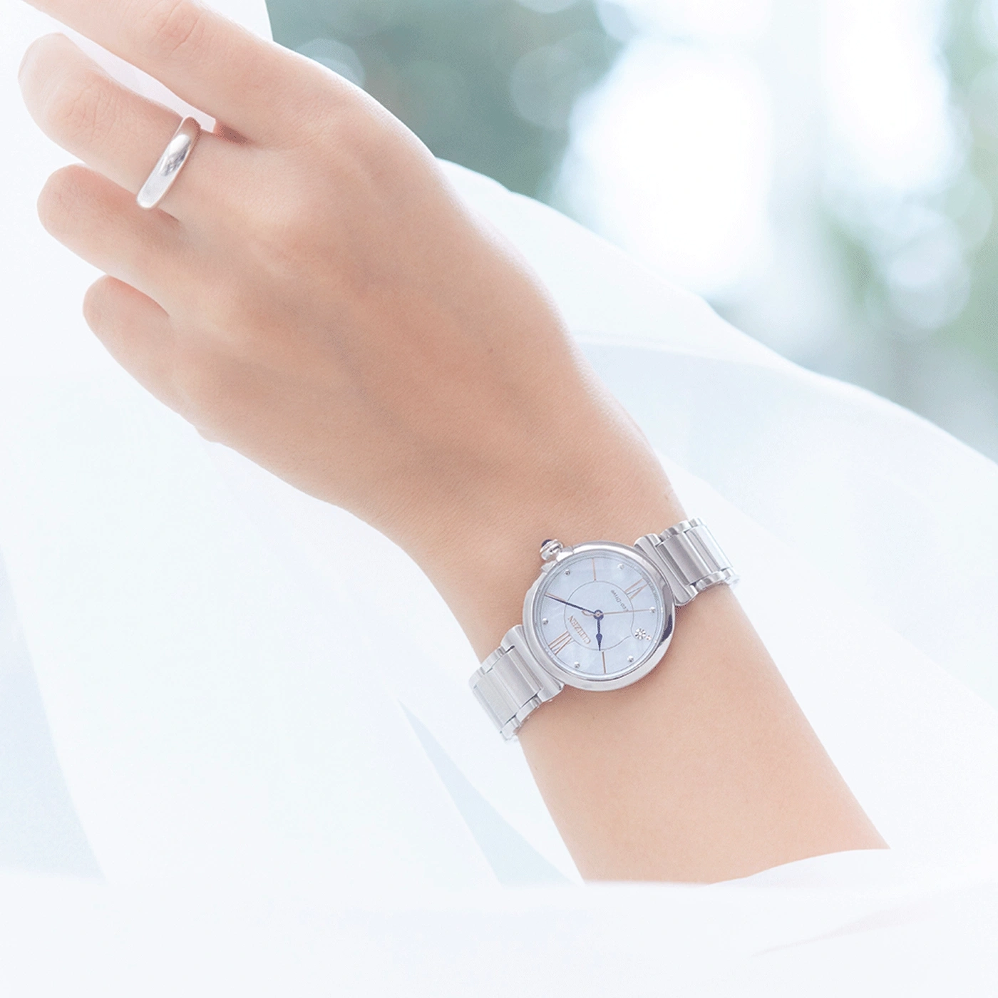 Pols met zilveren horloge en ring, witte achtergrond, elegant