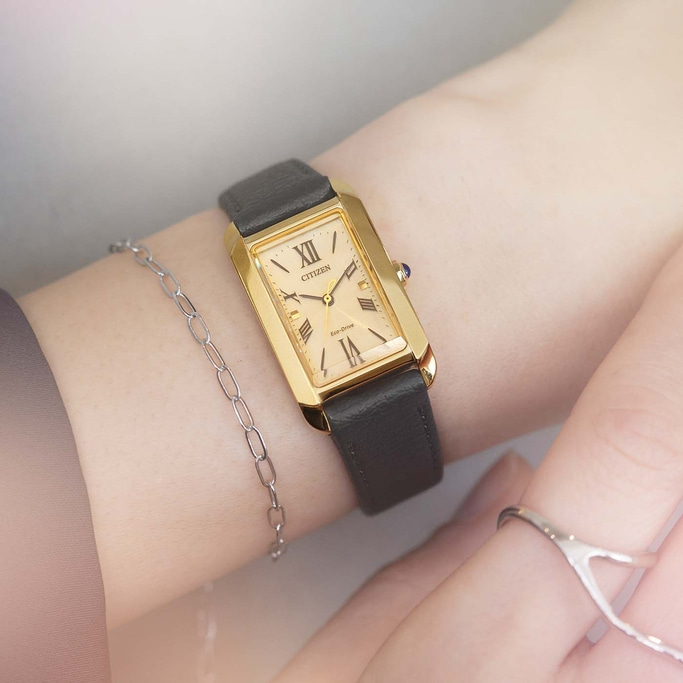 Gouden horloge om de pols met zwarte band en zilveren armband