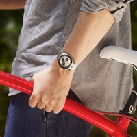 Persoon in grijs shirt houdt rode fietsframe vast, draagt een horloge.