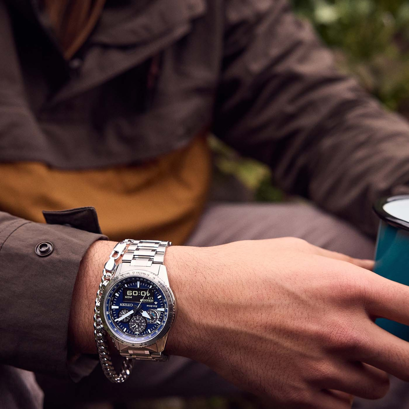 Man met Citizen horloge en armband, houdt een beker vast.