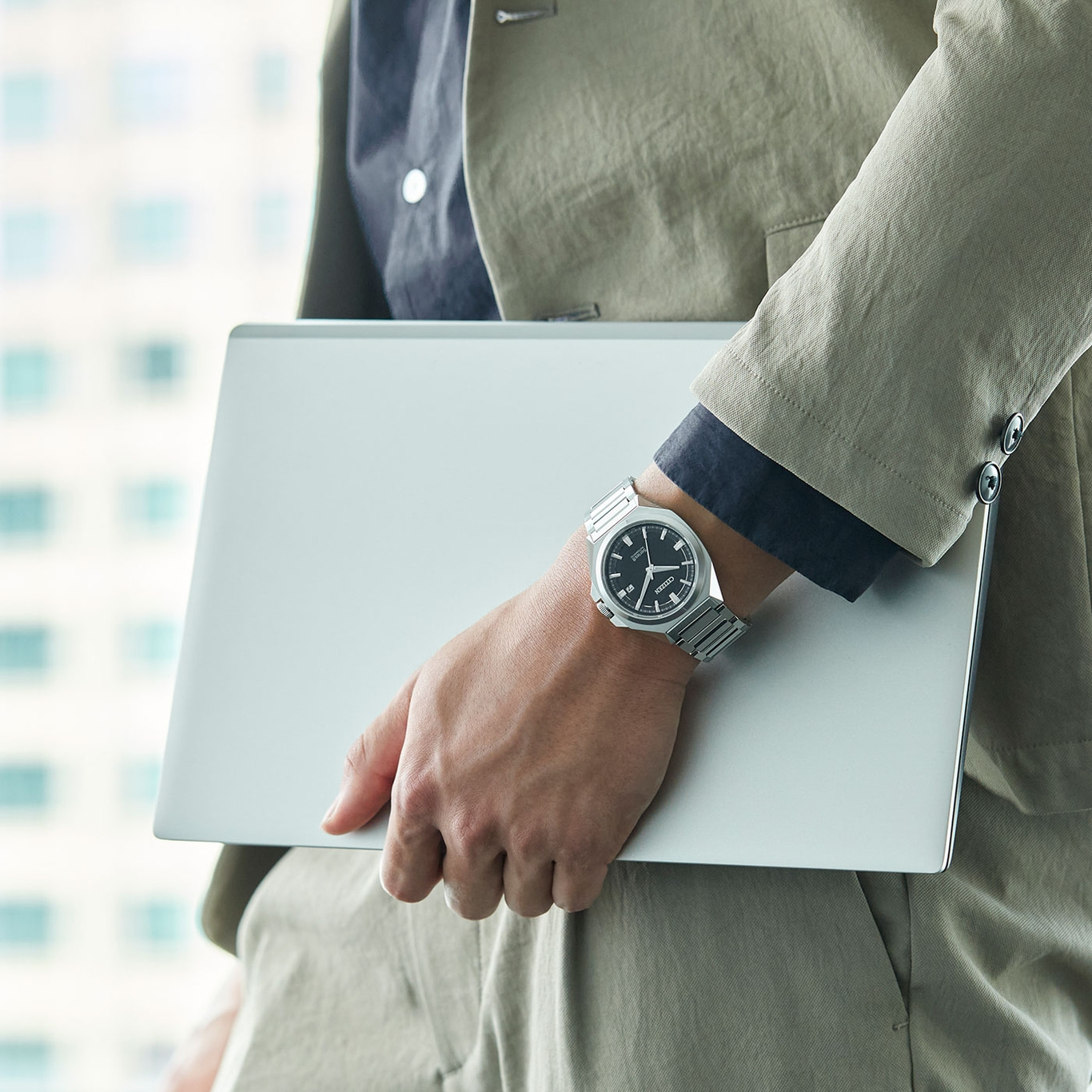 Man met laptop, draagt horloge en pak. Zakelijke professional.