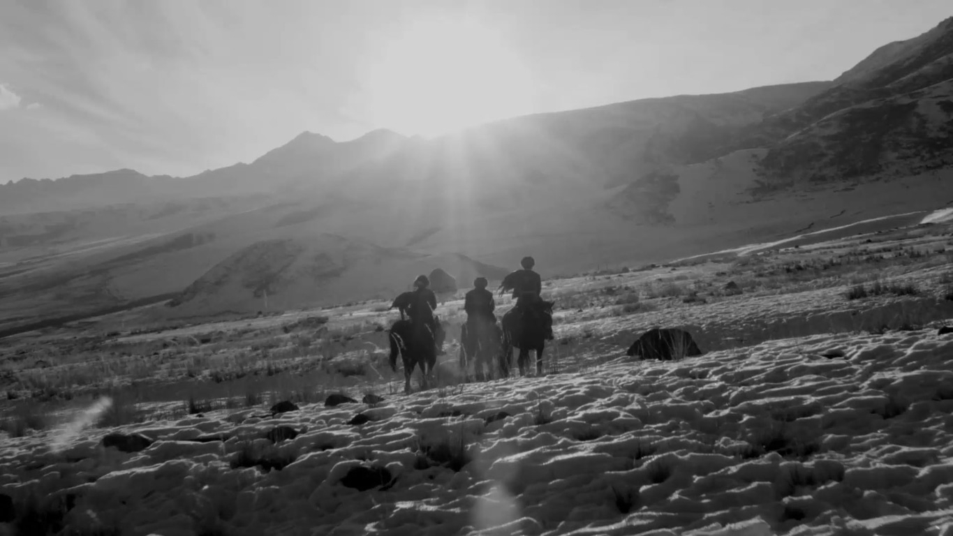 Paarden en ruiters in een besneeuwd berglandschap, zwart-wit fotografie.