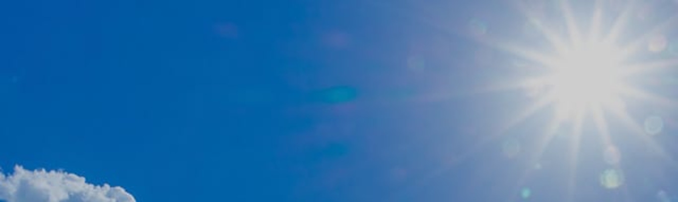 Felle zon in een heldere blauwe lucht met een paar wolken.