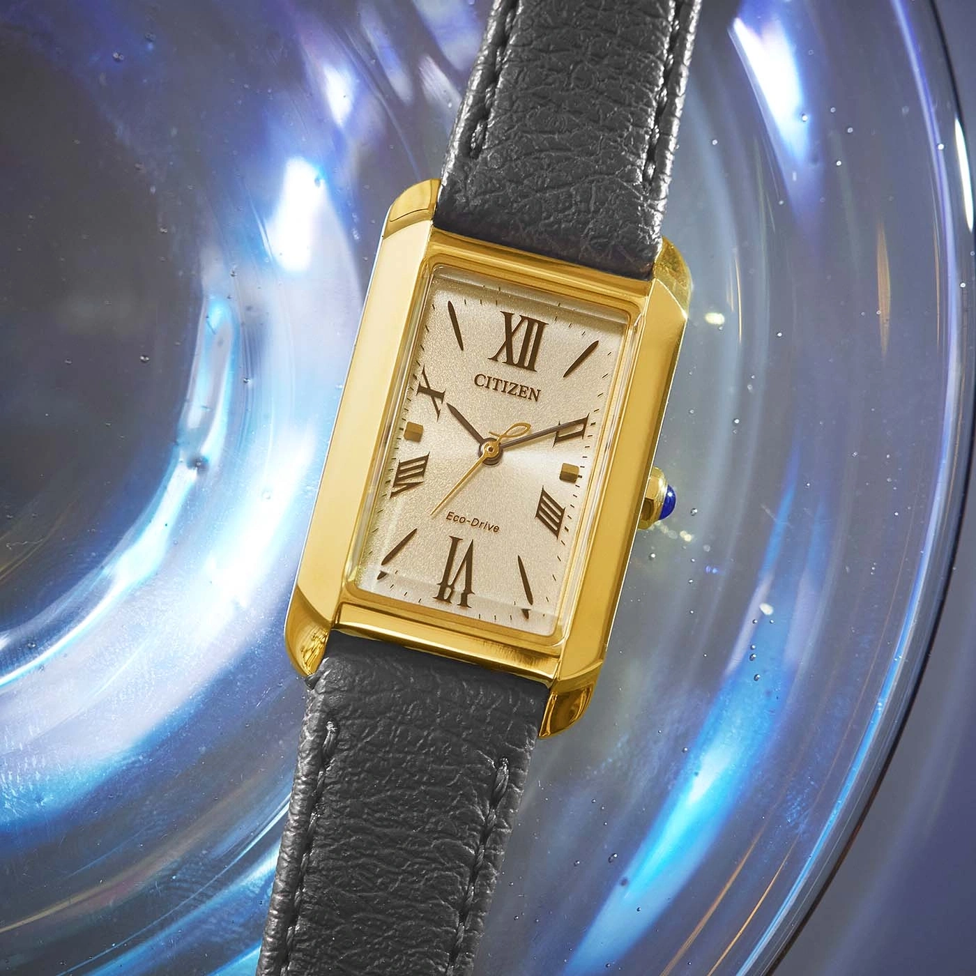 Citizen horloge met gouden kast en zwarte leren band op een blauwe achtergrond