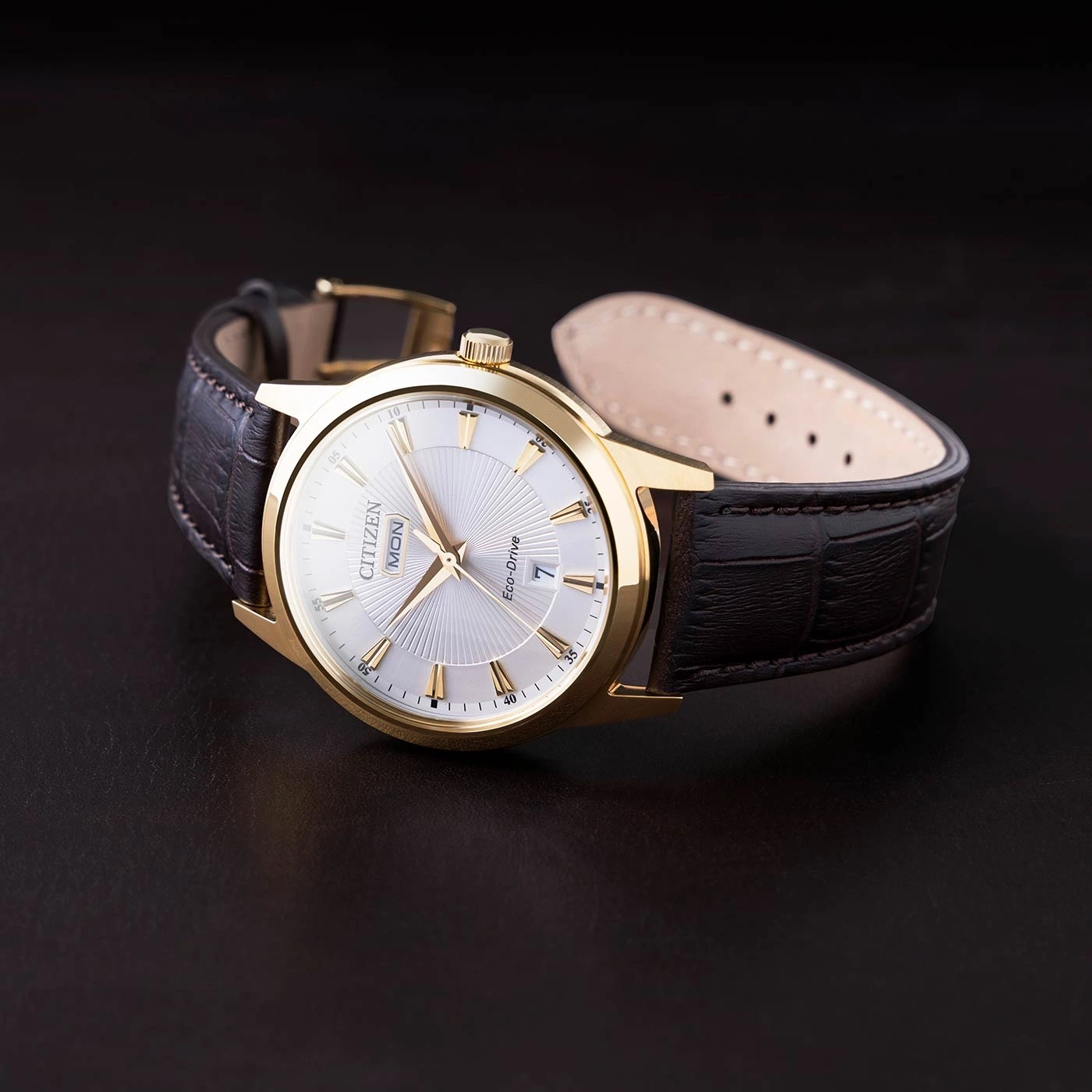 Gouden Citizen horloge met leren band op een donker oppervlak.