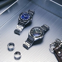 Twee horloges, ringen en een sleutelhanger op een getextureerd oppervlak.