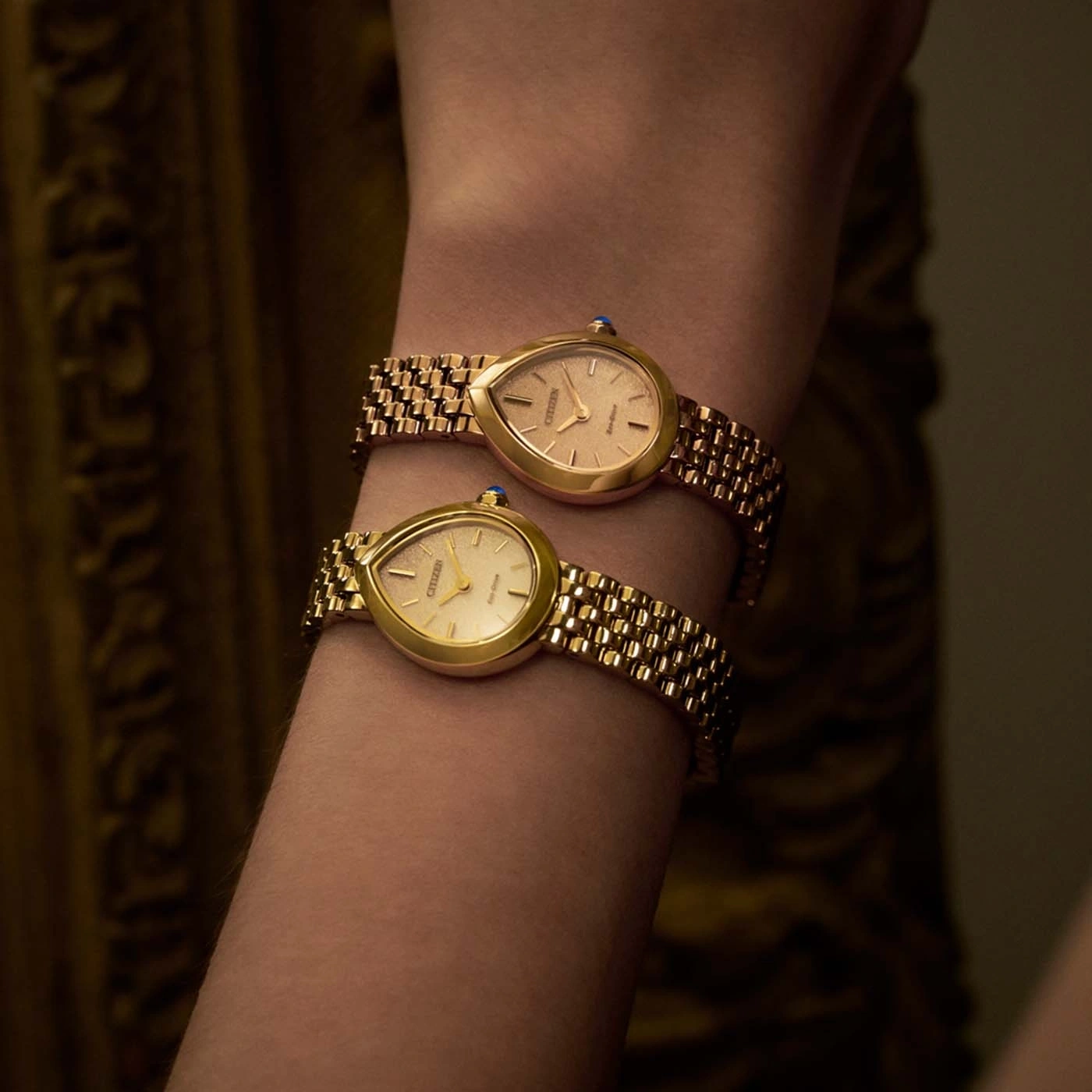 Twee gouden Citizen horloges aan een pols.