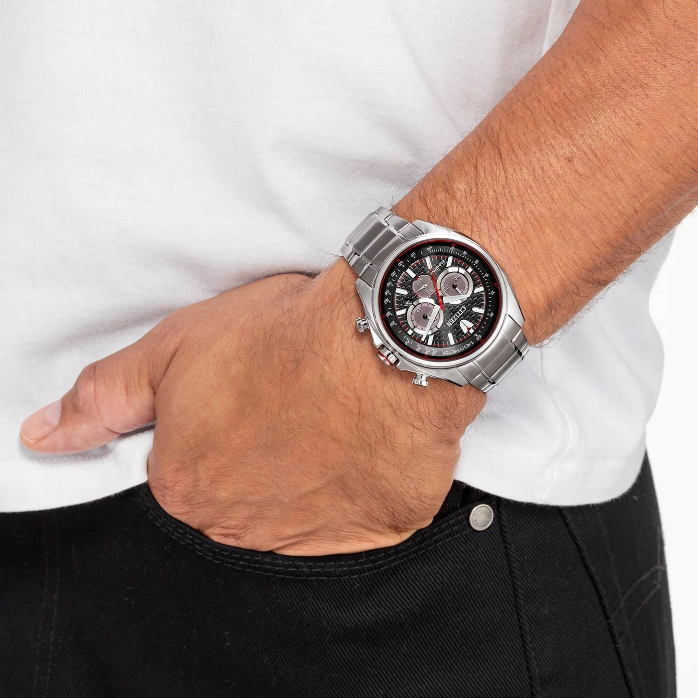 Man met zilveren Citizen horloge, wit shirt, zwarte jeans, hand in zak.