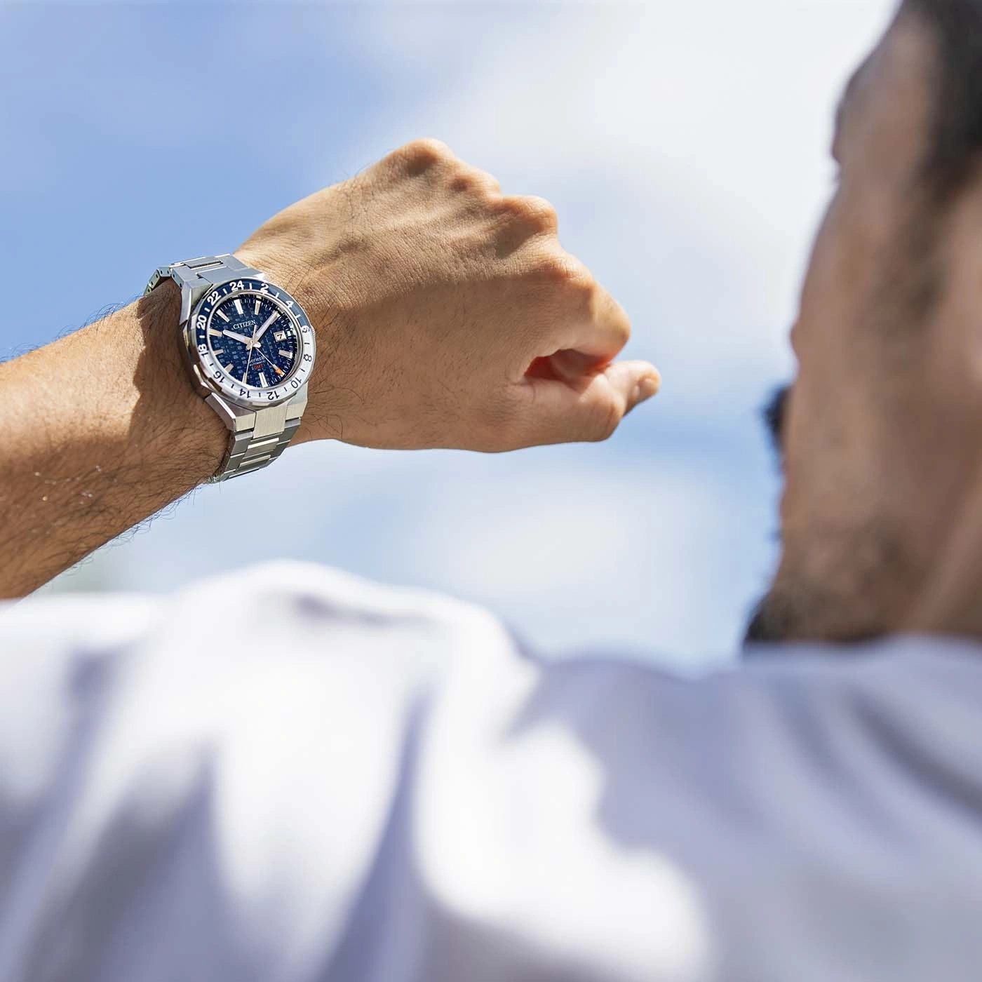 Man kijkt naar zijn horloge, blauwe lucht op de achtergrond, Citizen horloge
