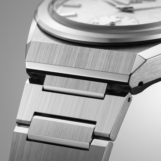 Close-up van een zilveren horloge met een geborstelde metalen afwerking en een gedetailleerd ontwerp.