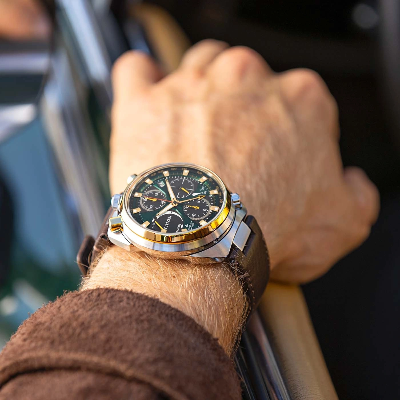 Een man draagt een Citizen-horloge om zijn pols en rijdt in een auto.