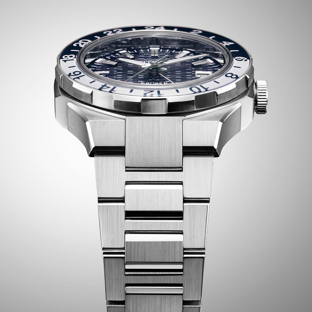 Close-up van een zilveren horloge met een blauw-witte bezel en een metalen band.