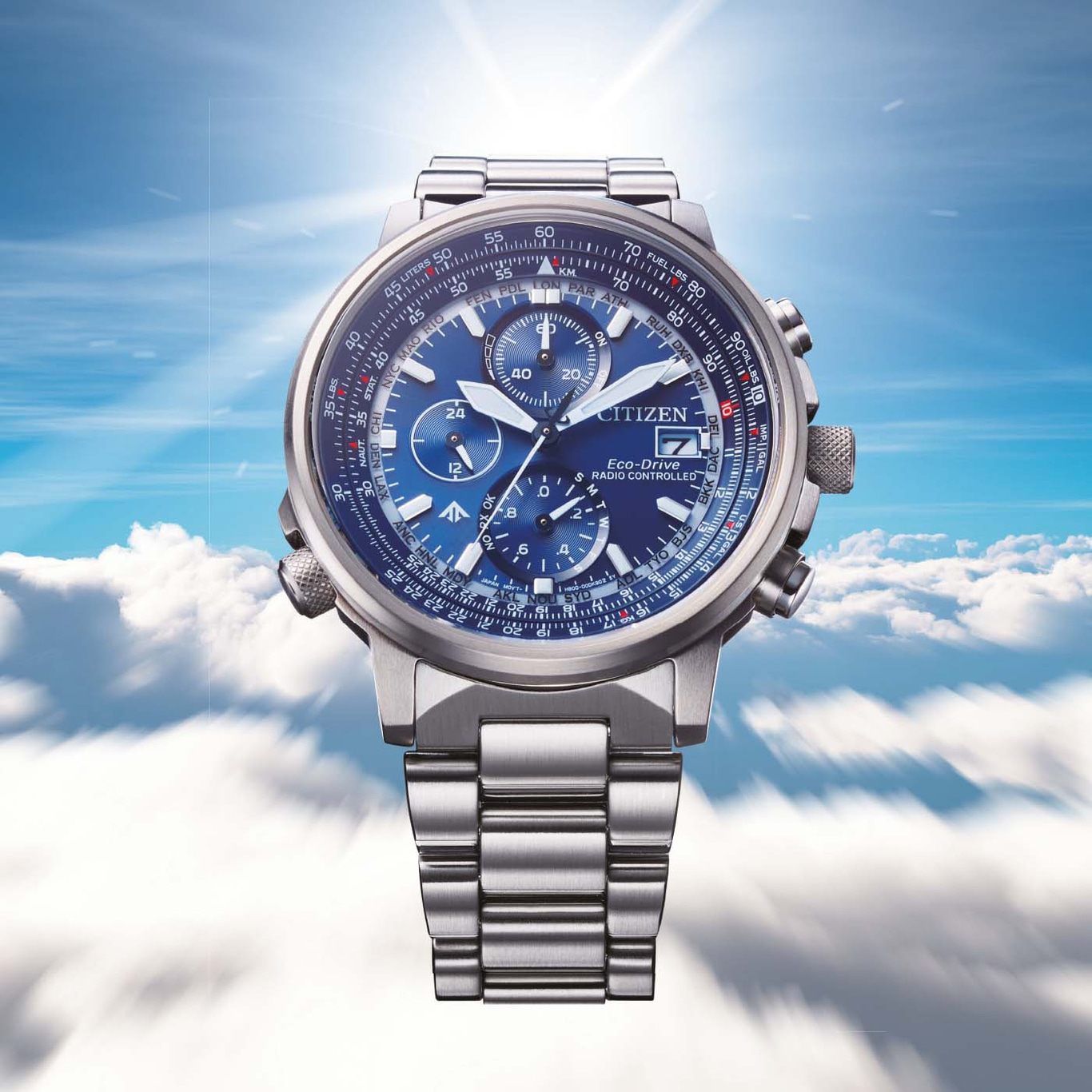 Citizen horloge met blauwe wijzerplaat, roestvrijstalen band en lucht achtergrond.