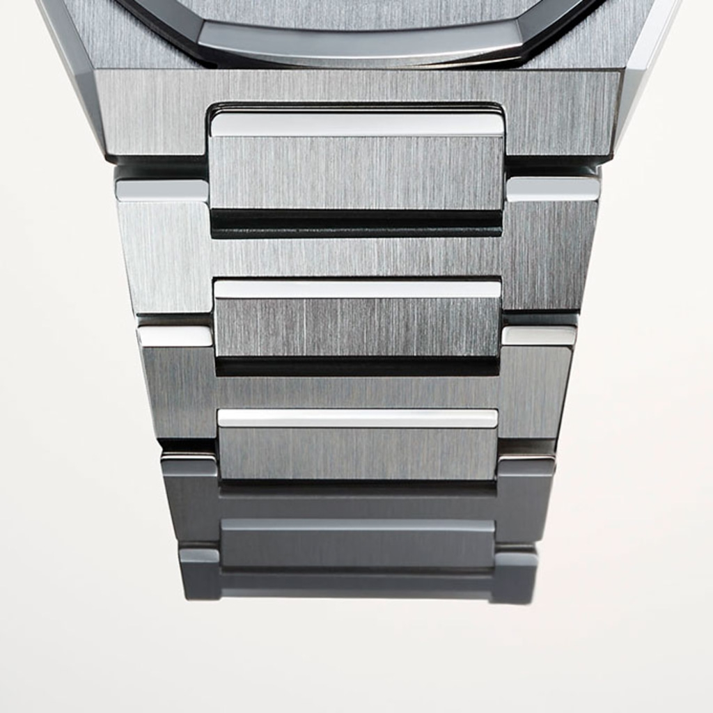 Close-up van een metalen horlogeband met geborstelde metalen afwerking en witte accenten.