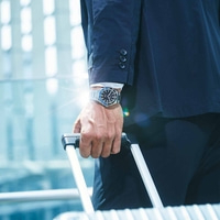 Man in pak met horloge die bagage vasthoudt, concept van zakenreizen.
