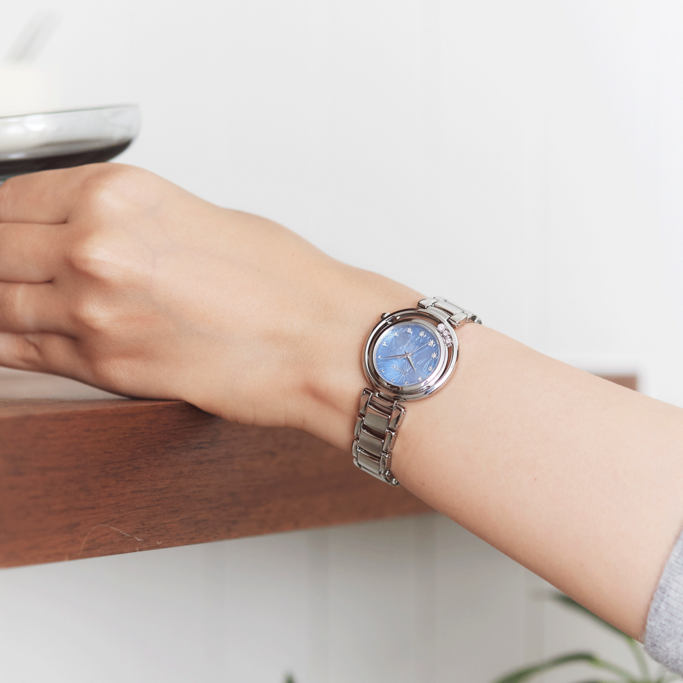 Een pols met een zilveren horloge, blauwe wijzerplaat en sneeuwvlokkenontwerp.