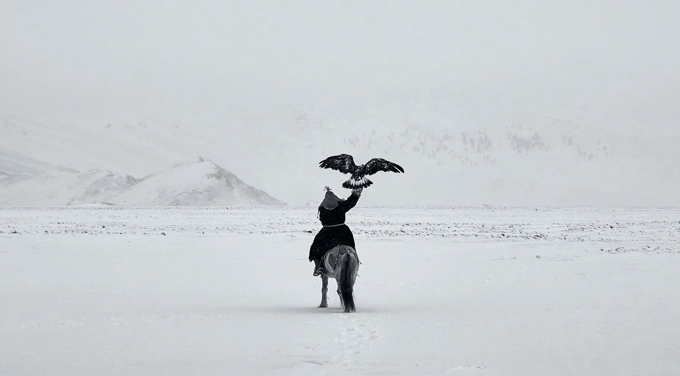 Man te paard met adelaar in besneeuwd landschap, monochroom.