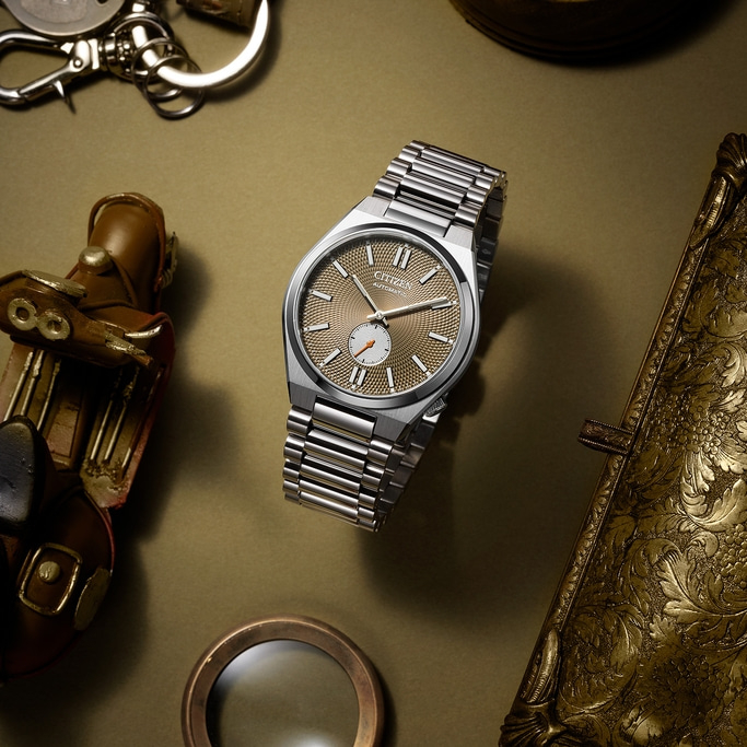 Citizen horloge met gouden wijzerplaat, omringd door vintage accessoires.