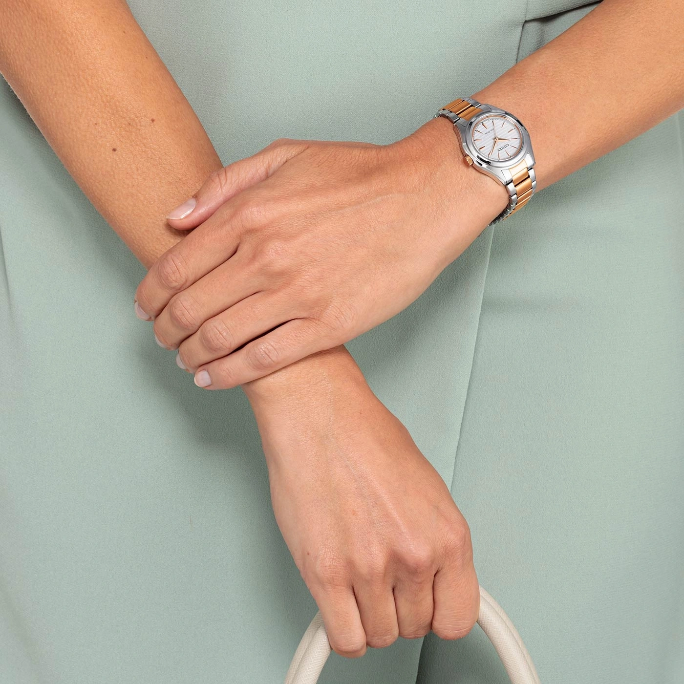 Vrouw met horloge, handtas, lichtgroene jurk, gekruiste handen