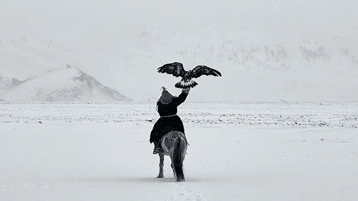 Een man te paard met een adelaar in een besneeuwd landschap.