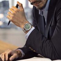 Man in pak met horloge en pen aan bureau
