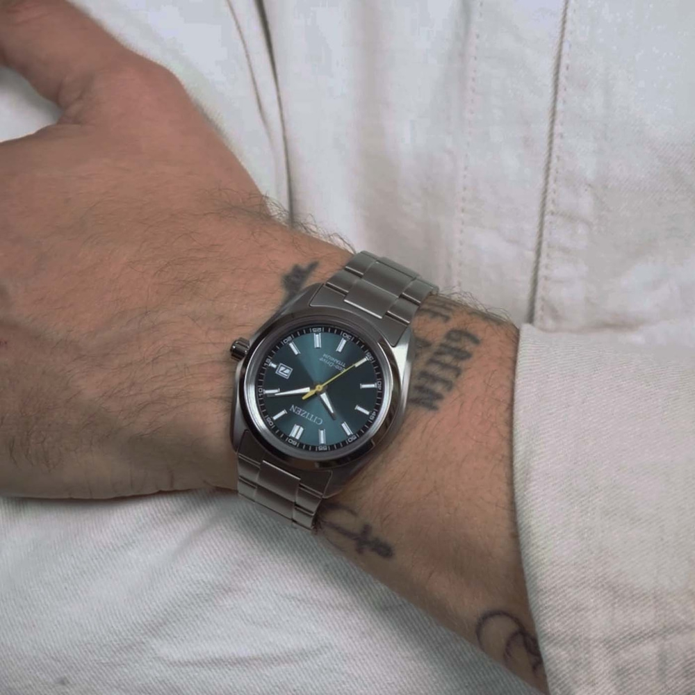 Een mannenpols met een Citizen Eco-Drive horloge en tatoeages.