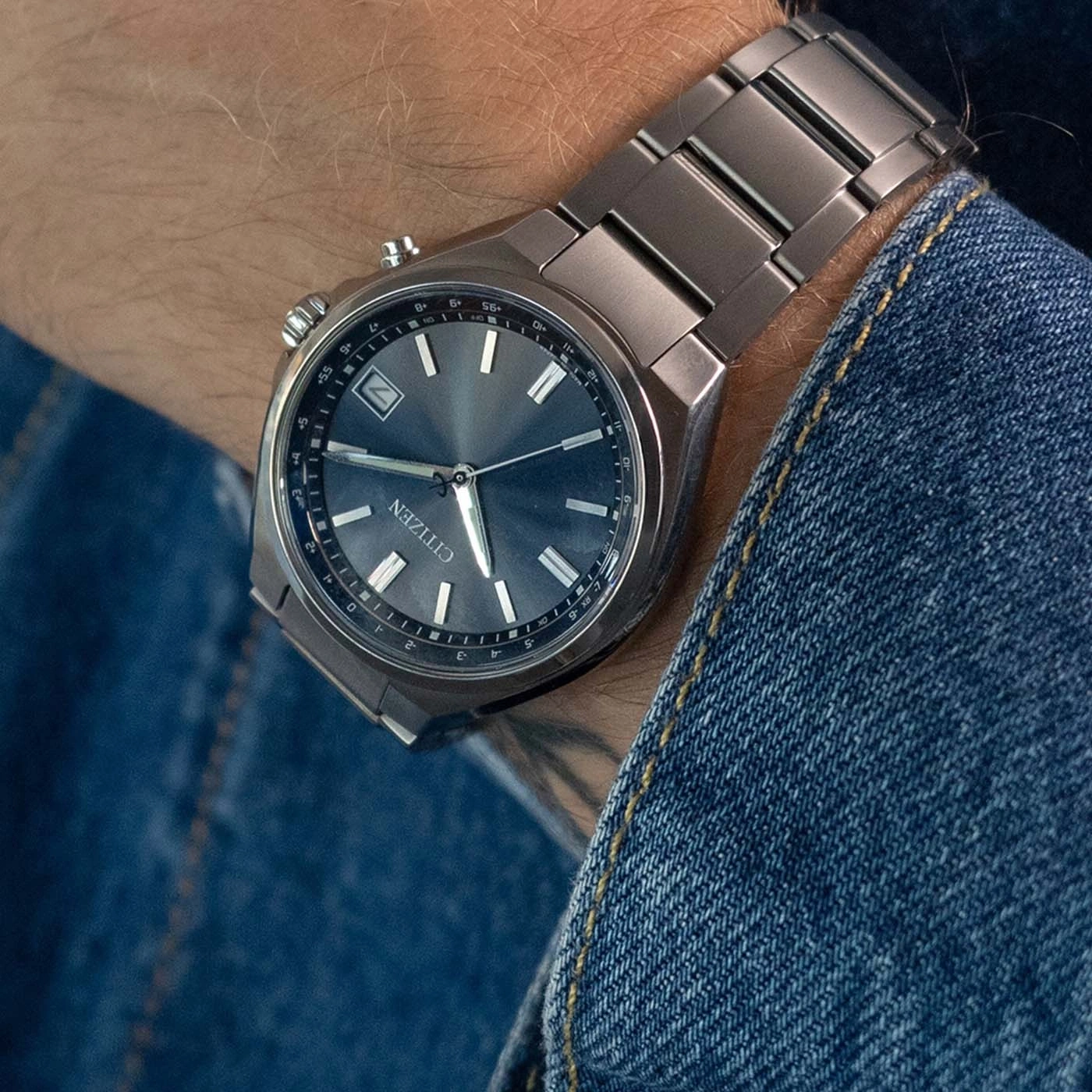 Een man draagt een Citizen horloge om zijn pols, met wijzerplaat en metalen band.